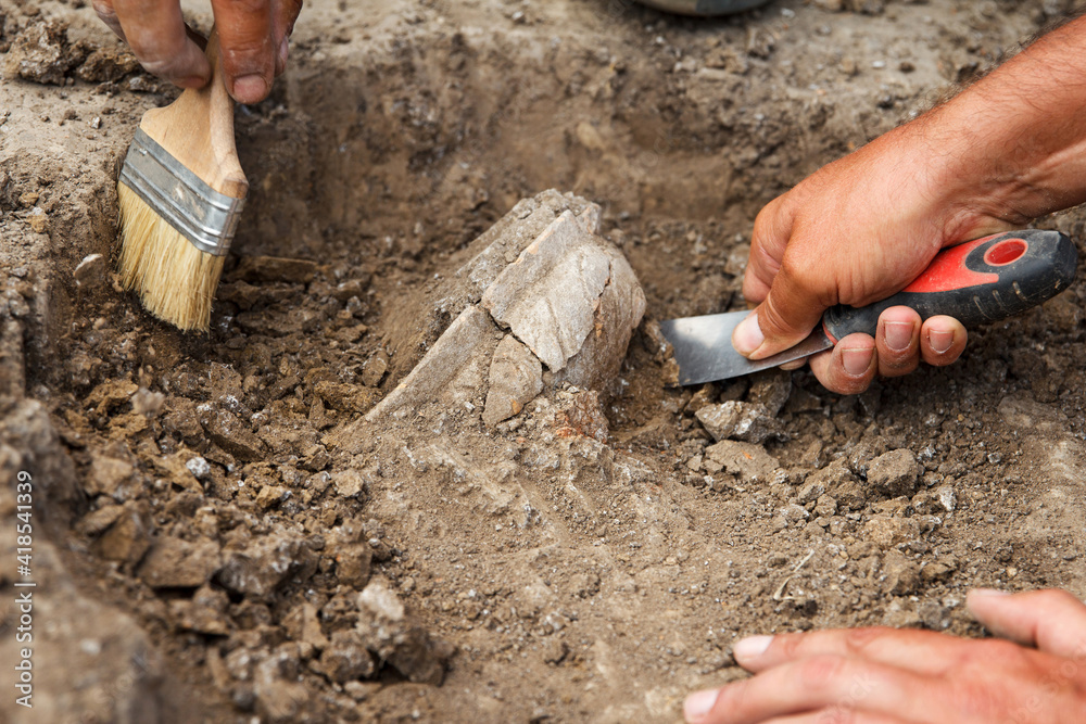 Archaeological excavations, archaeologists work, dig up an ancient clay artifact with special tools