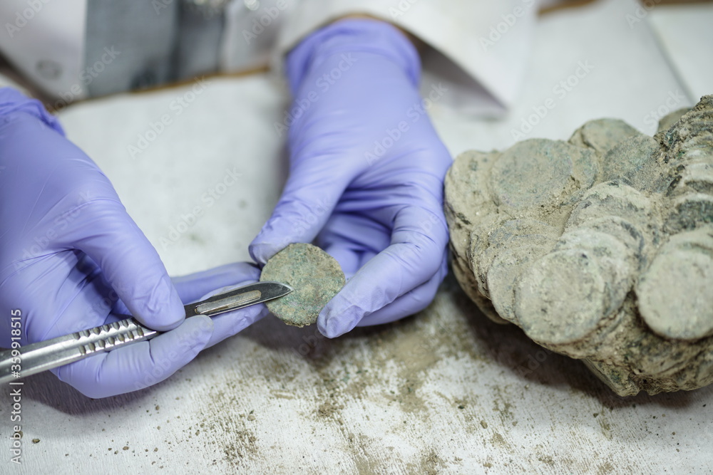 woman restoring ancient coins . Restorer, conservation. Archaeological background.